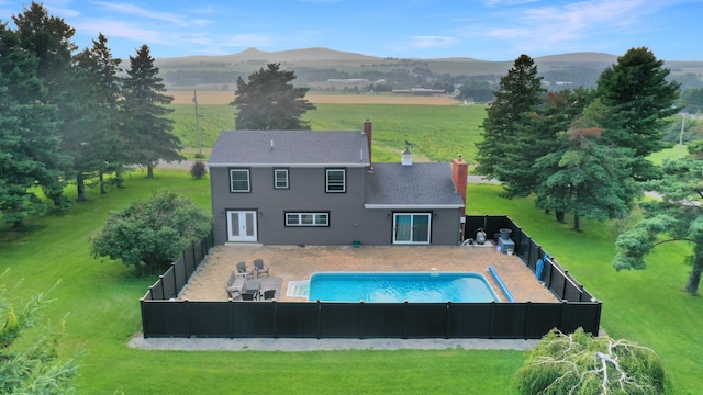 rear view of property featuring a fenced in pool, a rural view, and a mountain view