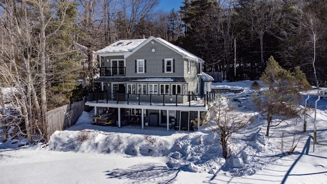 snow covered back of property featuring fence and a deck