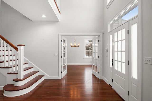 foyer entrance featuring dark wood-style floors, french doors, a high ceiling, baseboards, and stairs