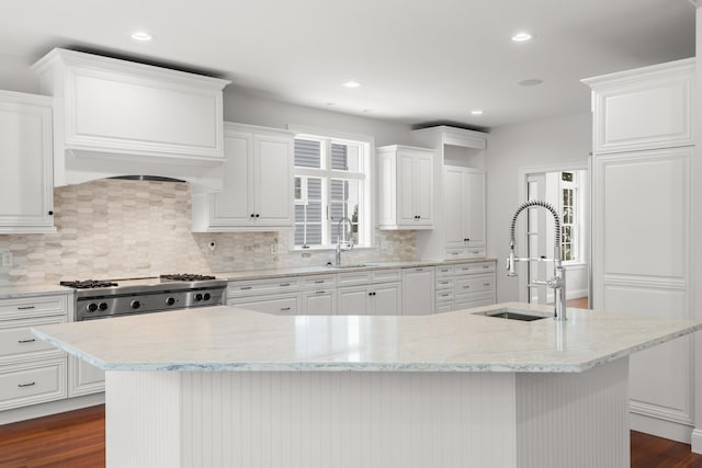 kitchen with a kitchen island with sink and white cabinetry