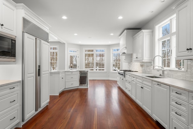 kitchen featuring white cabinets, a sink, and built in appliances