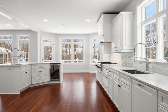 kitchen with wine cooler, dark wood-type flooring, a sink, and white cabinetry