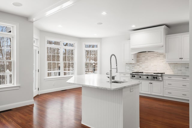 kitchen featuring stainless steel gas cooktop, dark wood-type flooring, white cabinetry, a sink, and an island with sink