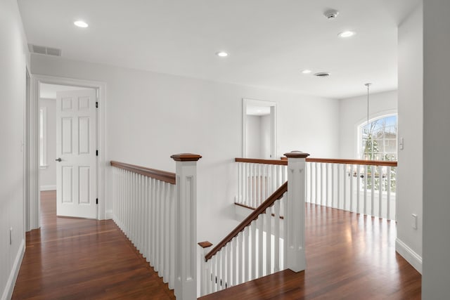 hallway with dark wood-type flooring, an upstairs landing, visible vents, and recessed lighting