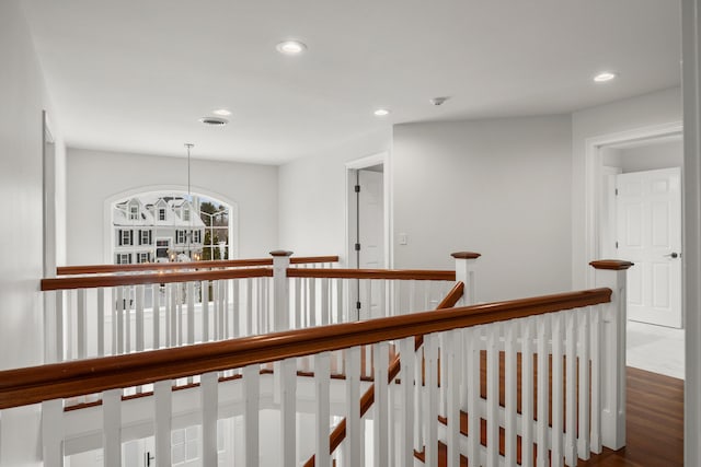 hallway featuring an upstairs landing, visible vents, wood finished floors, and recessed lighting