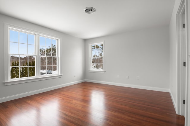 unfurnished room featuring dark wood finished floors, visible vents, and baseboards