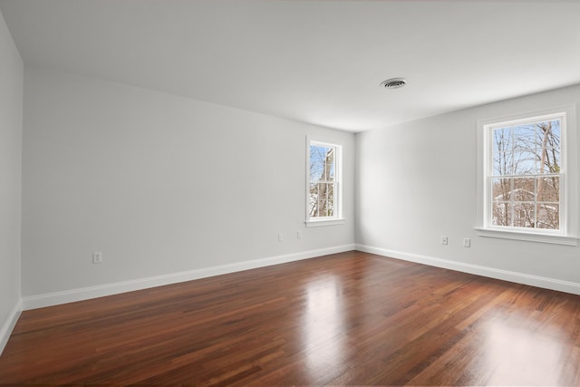 spare room with visible vents, dark wood finished floors, and baseboards