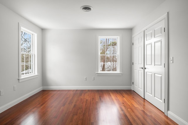 unfurnished bedroom featuring baseboards, a closet, visible vents, and dark wood-style flooring