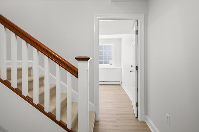 stairway with baseboards, baseboard heating, and wood finished floors