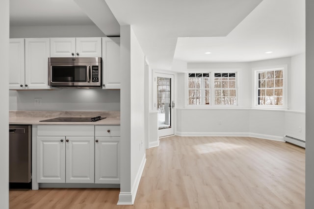 kitchen with a baseboard radiator, white cabinets, light countertops, appliances with stainless steel finishes, and light wood-type flooring