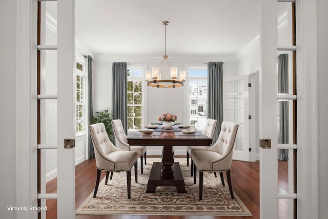 dining space with ornamental molding, a notable chandelier, and wood finished floors