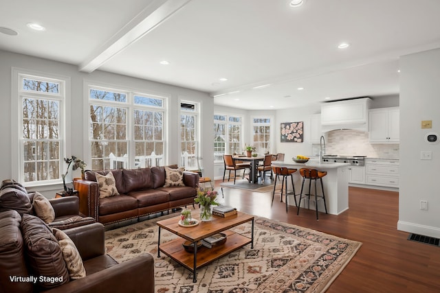 living room featuring visible vents, baseboards, dark wood-style floors, beamed ceiling, and recessed lighting