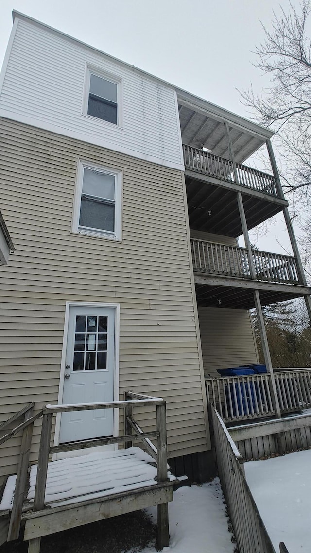 snow covered back of property featuring a balcony