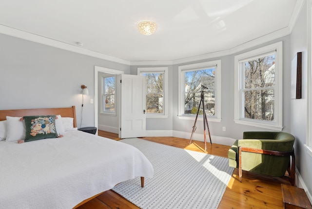 bedroom with crown molding, baseboards, and wood finished floors