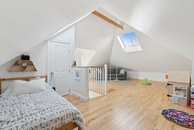 bedroom with lofted ceiling with skylight, wood finished floors, and baseboards