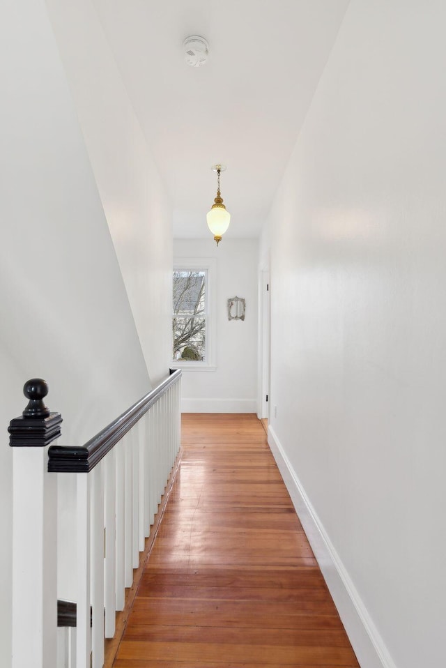 corridor featuring an upstairs landing, baseboards, and light wood-style flooring