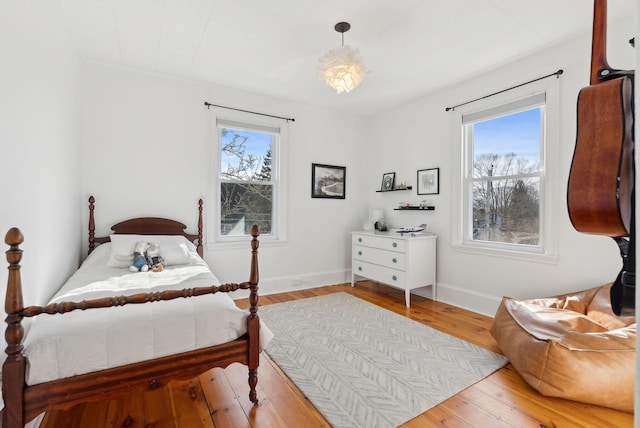 bedroom with baseboards, multiple windows, and hardwood / wood-style flooring