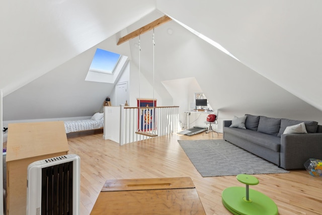 interior space with heating unit, vaulted ceiling with skylight, and wood finished floors