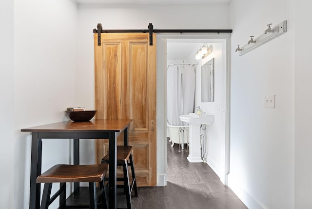 hall featuring a barn door and baseboards