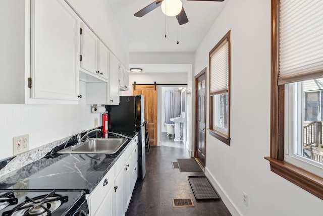 kitchen with baseboards, visible vents, a sink, white cabinetry, and a barn door