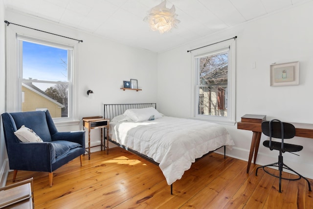 bedroom with baseboards, multiple windows, and light wood-style flooring