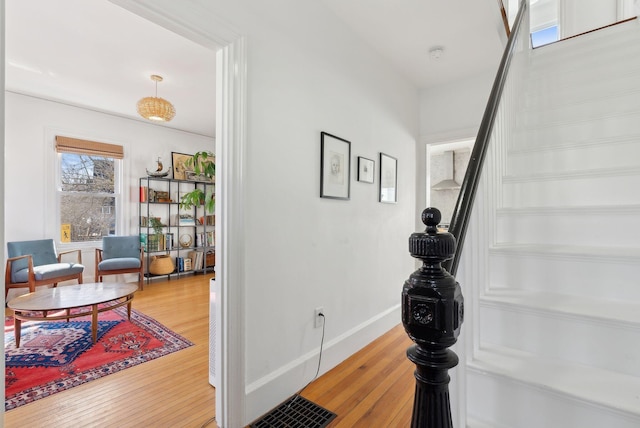 corridor with stairway, wood finished floors, and baseboards