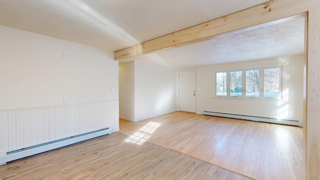 spare room with beamed ceiling, a baseboard heating unit, and light hardwood / wood-style floors