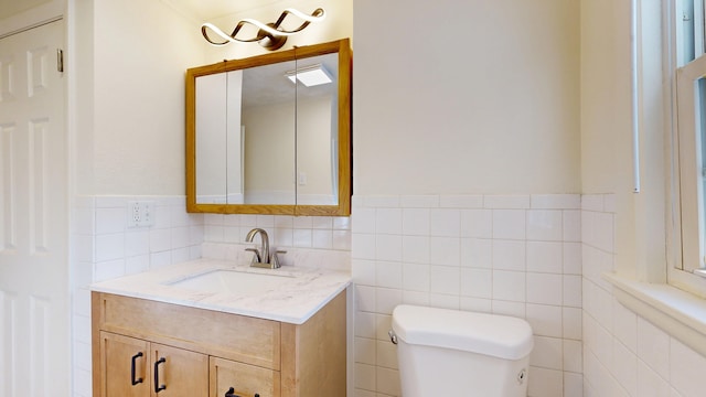 bathroom with vanity, tile walls, and toilet