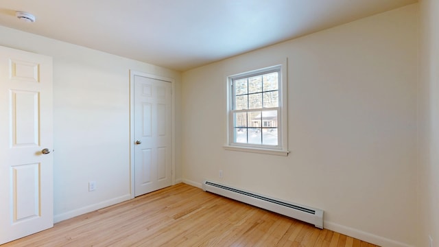 empty room with a baseboard radiator and light wood-type flooring