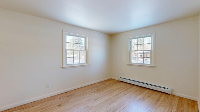 spare room featuring a baseboard heating unit and light hardwood / wood-style floors