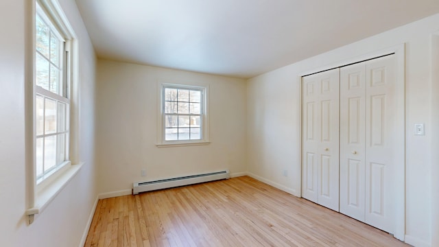 unfurnished bedroom with a baseboard radiator, a closet, and light hardwood / wood-style flooring