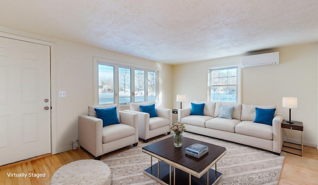 living room featuring hardwood / wood-style floors, a textured ceiling, and an AC wall unit