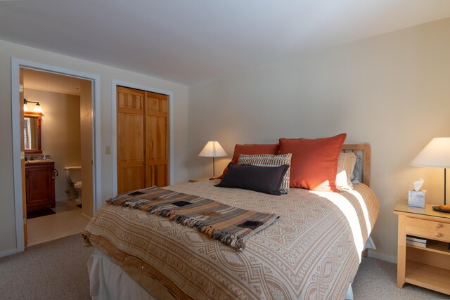 carpeted bedroom with ensuite bath and a closet