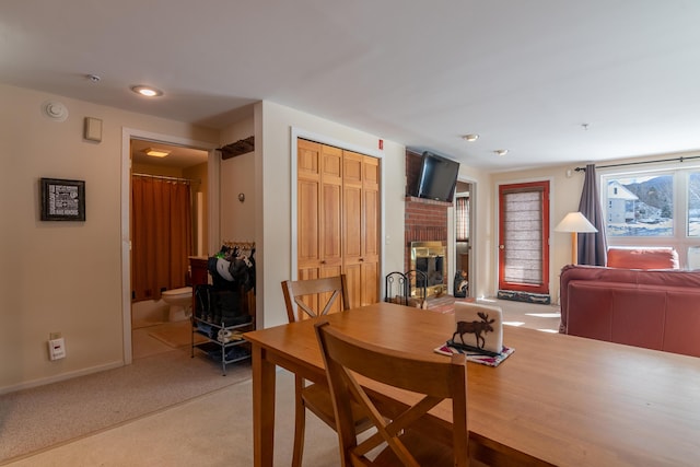 carpeted dining area with a fireplace