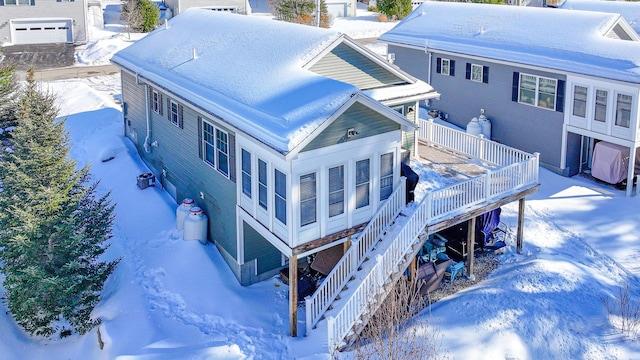 snow covered property featuring stairway and a wooden deck