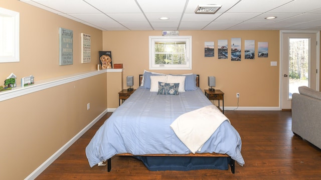 bedroom with dark wood-style floors, a drop ceiling, visible vents, and baseboards