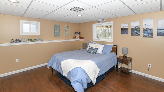 bedroom with dark wood-type flooring, a drop ceiling, visible vents, and baseboards