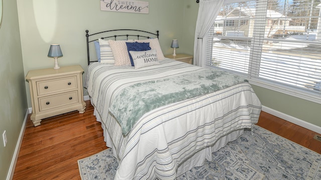 bedroom featuring multiple windows, baseboards, and wood finished floors