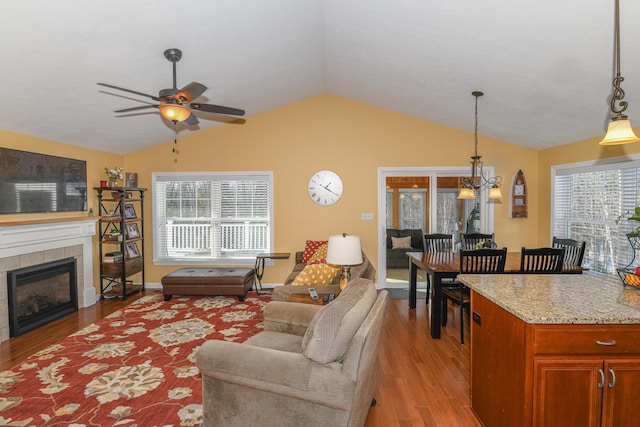 living room with lofted ceiling, light wood-style flooring, a tile fireplace, and a wealth of natural light