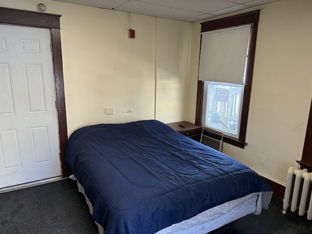 bedroom with a paneled ceiling and radiator