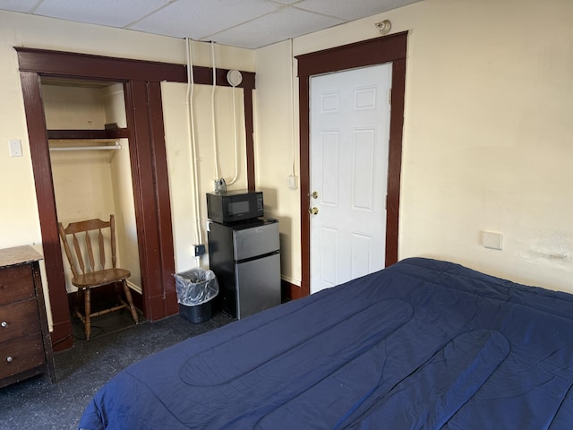 unfurnished bedroom with a paneled ceiling, stainless steel fridge, and a closet