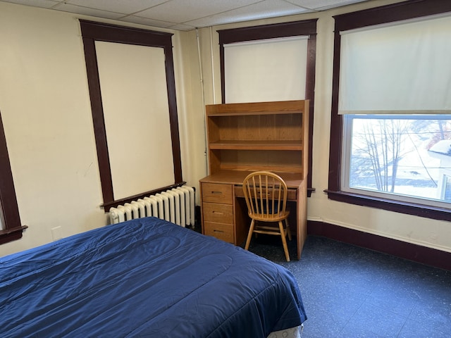 bedroom featuring built in desk, radiator heating unit, and a paneled ceiling