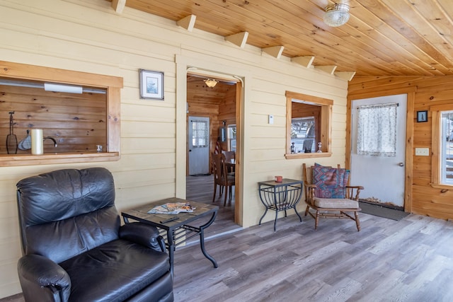 sitting room featuring wood ceiling, wood-type flooring, and wooden walls