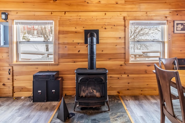 interior details featuring hardwood / wood-style flooring, wood walls, and a wood stove