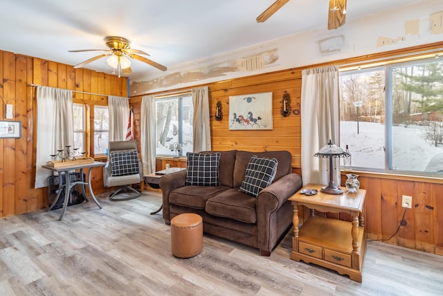 living room with wooden walls, light hardwood / wood-style floors, and ceiling fan