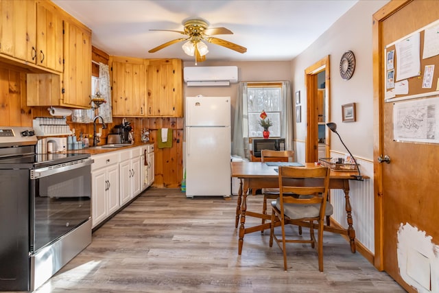 kitchen featuring sink, light hardwood / wood-style flooring, stainless steel range with electric stovetop, an AC wall unit, and white fridge