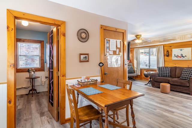 dining room featuring wooden walls, light hardwood / wood-style floors, and ceiling fan