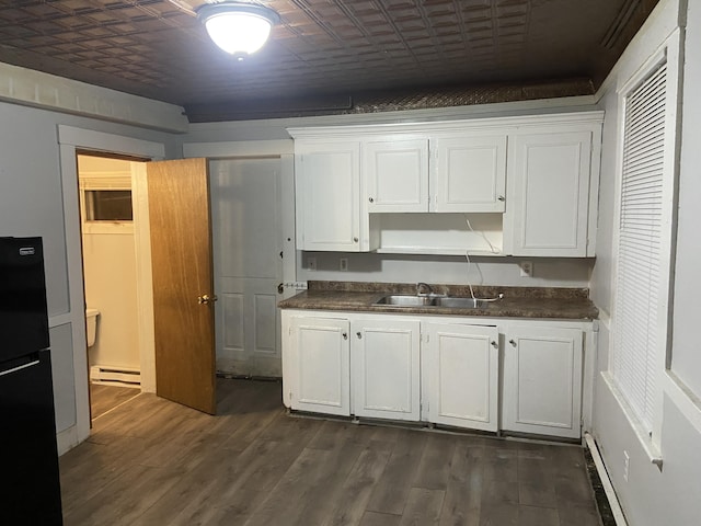 kitchen with sink, white cabinets, and black fridge