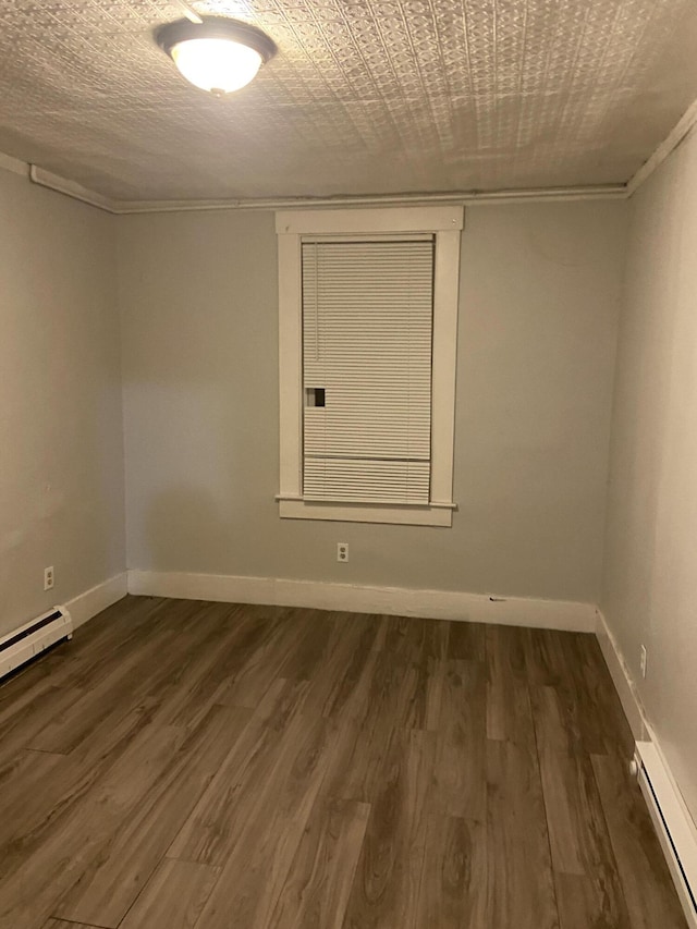 unfurnished room featuring a baseboard heating unit and dark hardwood / wood-style flooring