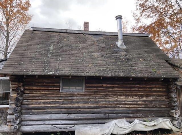 exterior details featuring a chimney and log siding